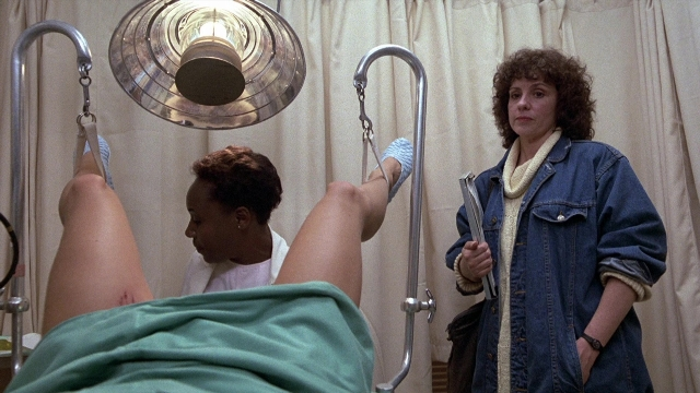 Wide shot frame from The Accused — standing, bed, lamp