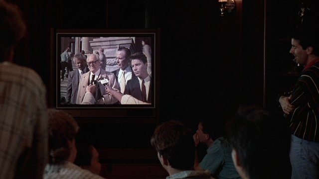 Wide shot frame from The Accused — sitting, standing, room