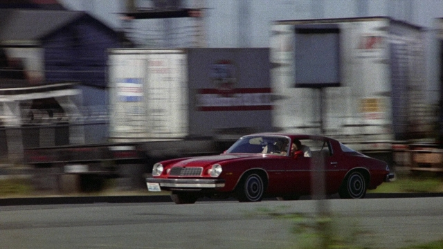 Wide shot frame from The Accused — street, car, wheel
