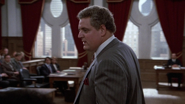 Medium shot frame from The Accused — sitting, standing, room
