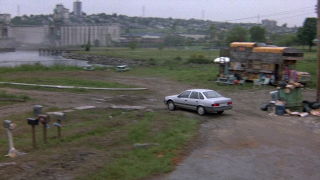 Wide shot frame from The Accused — street, car, water