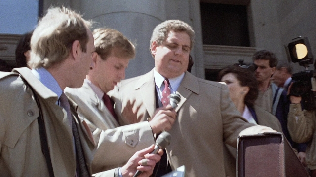 Wide shot frame from The Accused — dialogue, door, coat
