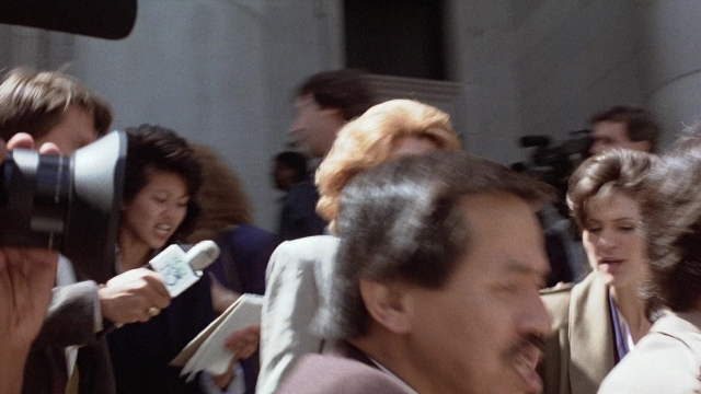 Medium shot frame from The Accused — suit, tie, mustache