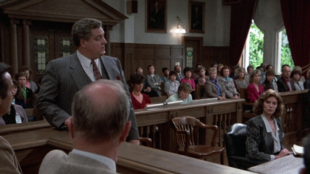 Wide shot frame from The Accused — sitting, standing, room