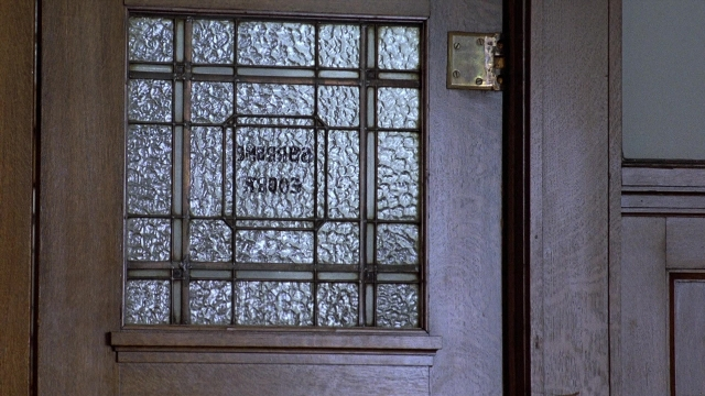Wide shot frame from The Accused — door, glass, window