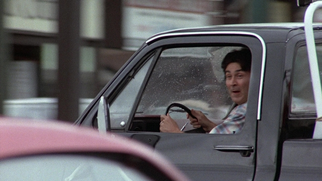 Wide shot frame from The Accused — street, car, shirt