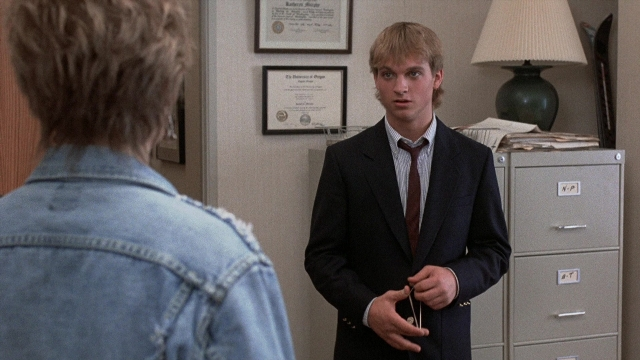Wide shot frame from The Accused — standing, suit, tie