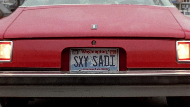 Wide shot frame from The Accused — plate, car, wheel