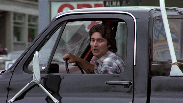 Wide shot frame from The Accused — sitting, door, street