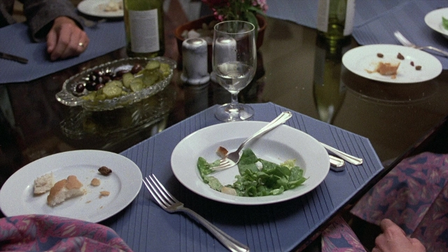 Frame from The Accused — sitting, table, food