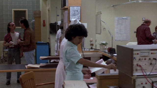 Wide shot frame from The Accused — sitting, standing, room