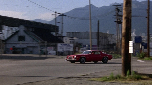 Wide shot frame from The Accused — street, car, running