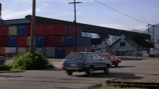 Frame from The Accused — street, car, house