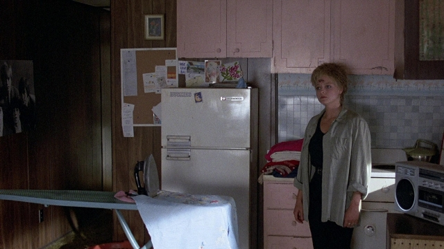 Wide shot frame from The Accused — standing, table, kitchen