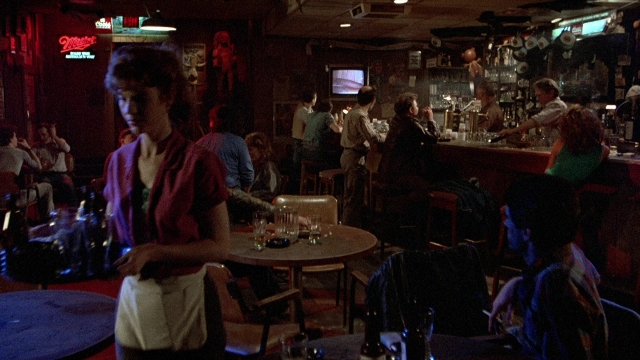 Wide shot frame from The Accused — sitting, standing, table
