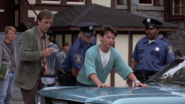 Wide shot frame from The Accused — standing, car, face