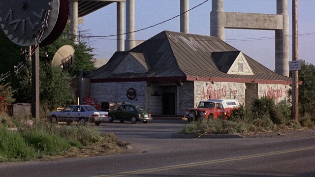 Frame from The Accused — street, car, house