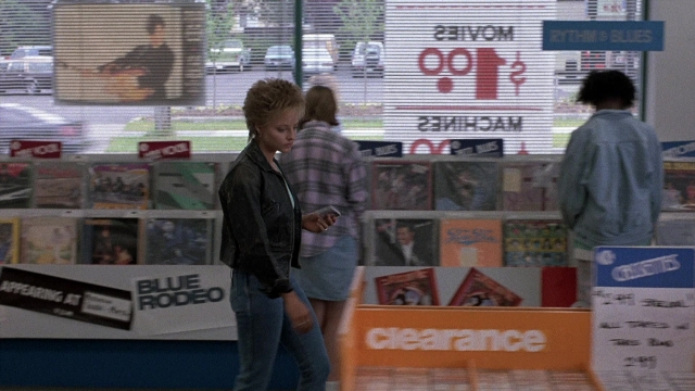 Wide shot frame from The Accused — standing, phone, shirt