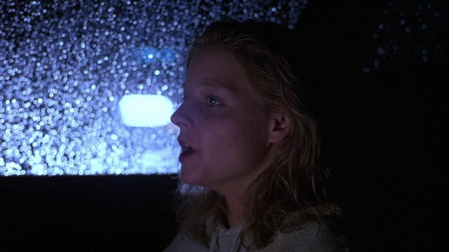 Frame from The Accused — standing, hair, person
