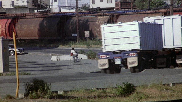 Wide shot frame from The Accused — street, car, bicycle