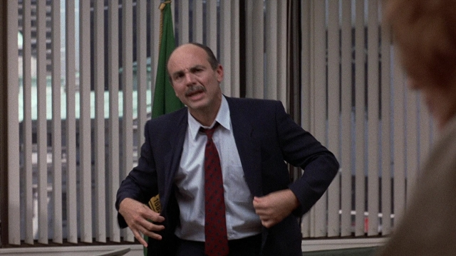 Wide shot frame from The Accused — standing, room, hand