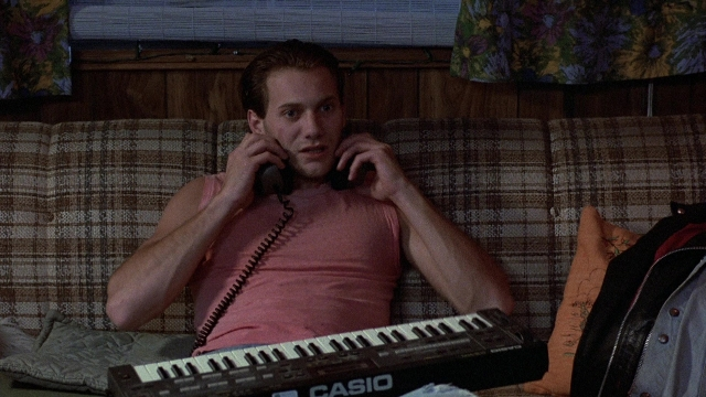 Wide shot frame from The Accused — sitting, phone, couch