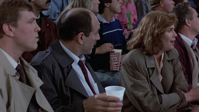 Frame from The Accused — sitting, dialogue, coat