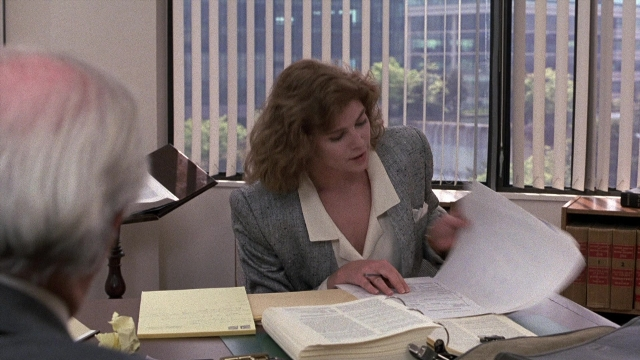 Wide shot frame from The Accused — sitting, book, office