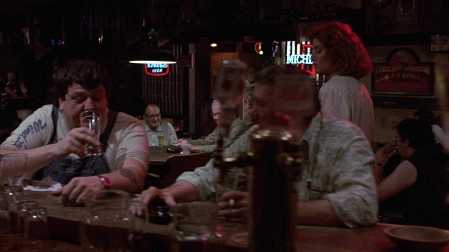 Wide shot frame from The Accused — sitting, standing, table