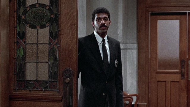 Wide shot frame from The Accused — standing, room, door