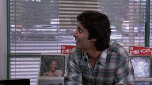 Wide shot frame from The Accused — sitting, shirt, office