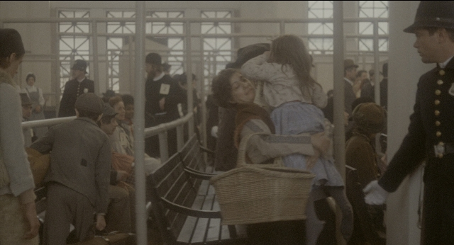Wide shot frame from The Godfather: Part II — sitting, standing, hat