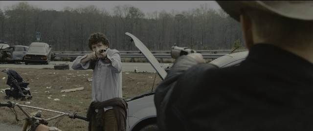 Wide shot frame from Zombieland — standing, street, hat