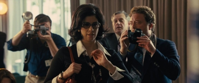 Wide shot frame from Battle of the Sexes — standing, room, suit