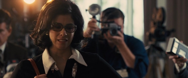 Medium shot frame from Battle of the Sexes — standing, room, suit