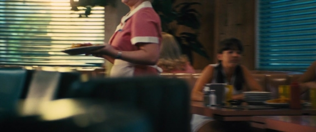 Wide shot frame from Battle of the Sexes — sitting, standing, table