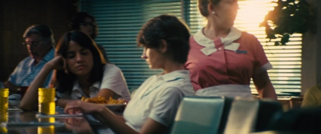 Wide shot frame from Battle of the Sexes — sitting, standing, table