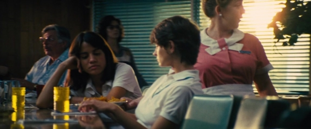 Wide shot frame from Battle of the Sexes — sitting, standing, plate