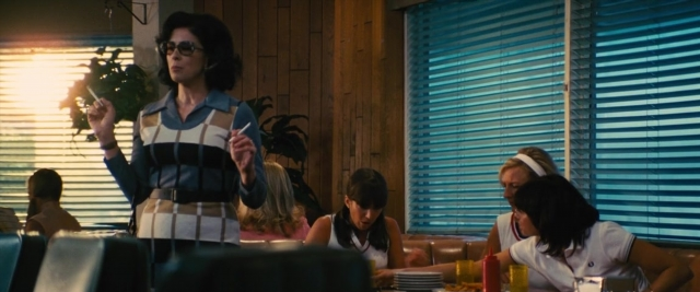 Wide shot frame from Battle of the Sexes — sitting, standing, room