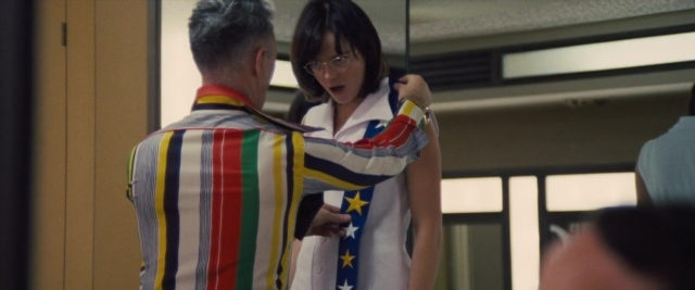 Wide shot frame from Battle of the Sexes — standing, room, dialogue