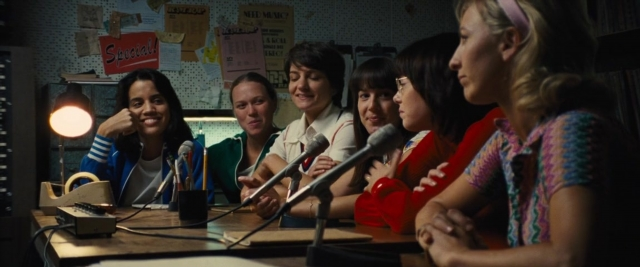 Wide shot frame from Battle of the Sexes — sitting, room, table