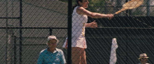 Wide shot frame from Battle of the Sexes — standing, hat, hand