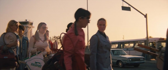 Wide shot frame from Battle of the Sexes — walking, street, car