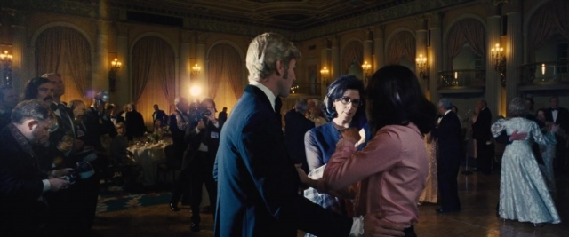 Wide shot frame from Battle of the Sexes — room, dialogue, suit