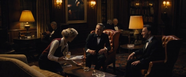Wide shot frame from Battle of the Sexes — sitting, room, table