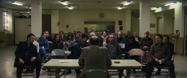 Wide shot frame from Battle of the Sexes — sitting, standing, room