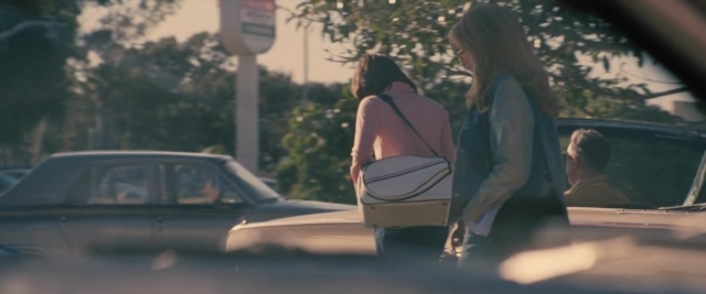 Wide shot frame from Battle of the Sexes — sitting, walking, street