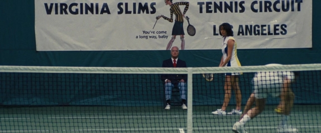 Medium shot frame from Battle of the Sexes — sitting, standing, suit