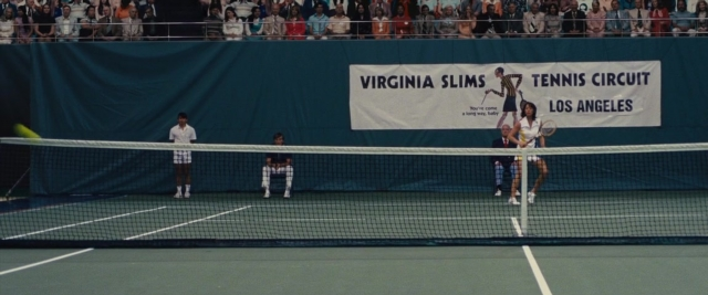 Wide shot frame from Battle of the Sexes — standing, person, tennis racket