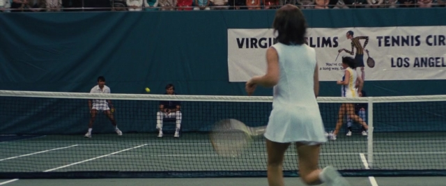 Frame from Battle of the Sexes — sitting, standing, hand